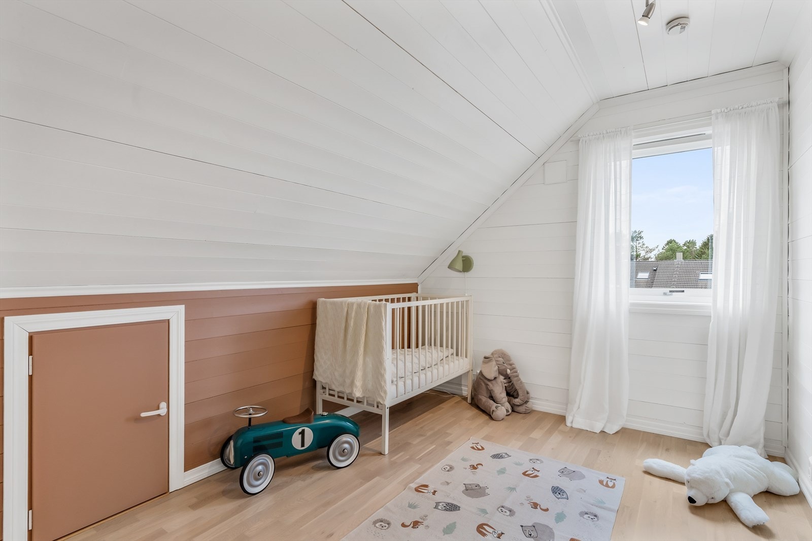 Et av de tre rommene i loftsetasjen, med skråtak og panel på veggene. Galleribilde