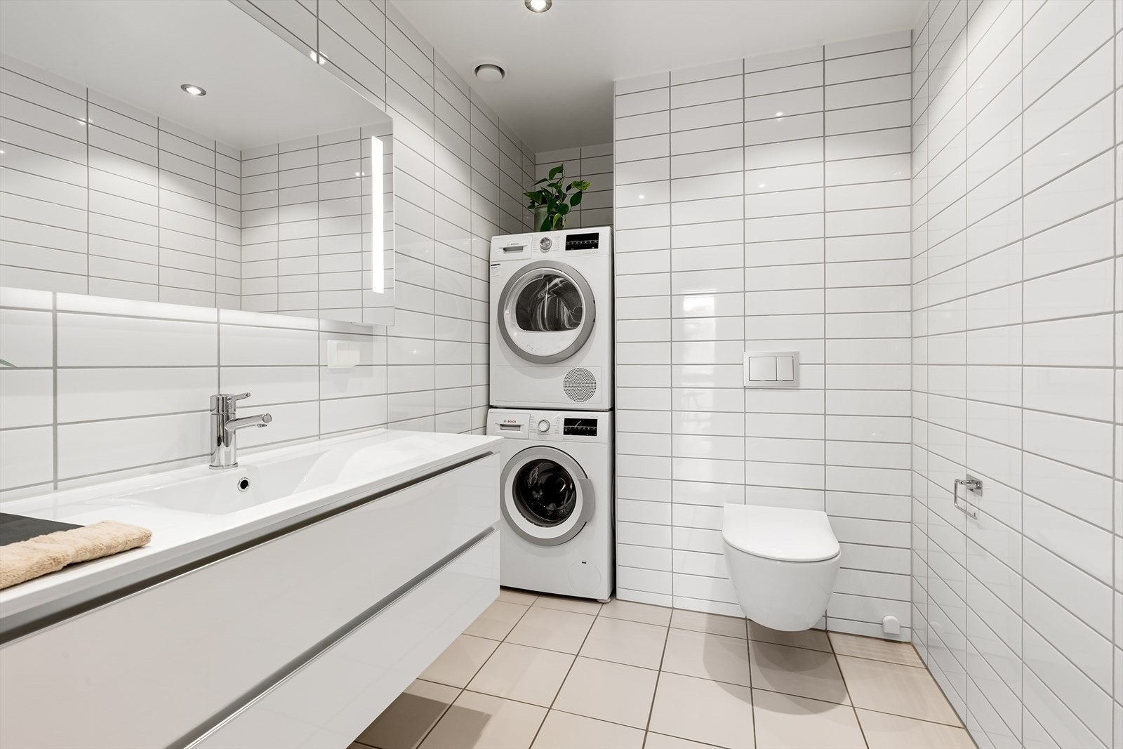Stort og praktisk baderom med lyse overflater og downlights Galleribilde