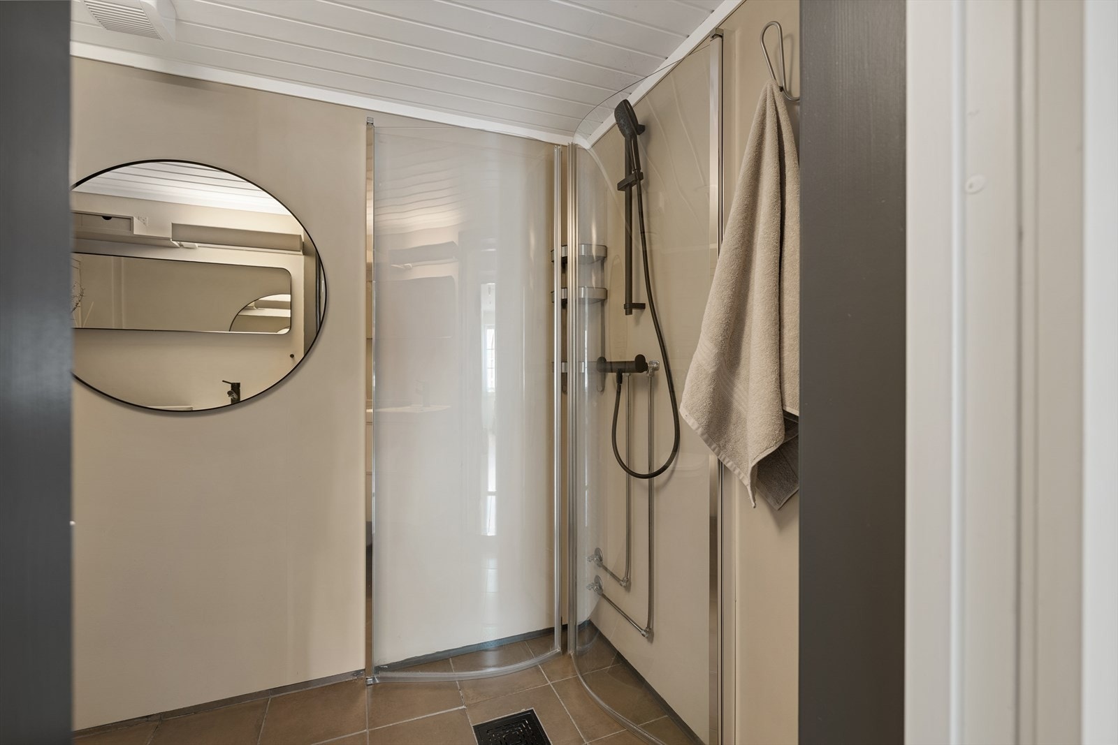 Badet har fliser på gulv, malte baderomsplater på vegger og panel i himling. Dusjhjørne med innskyvbare vegger, veggmontert wc og opplegg for vaskem Galleribilde
