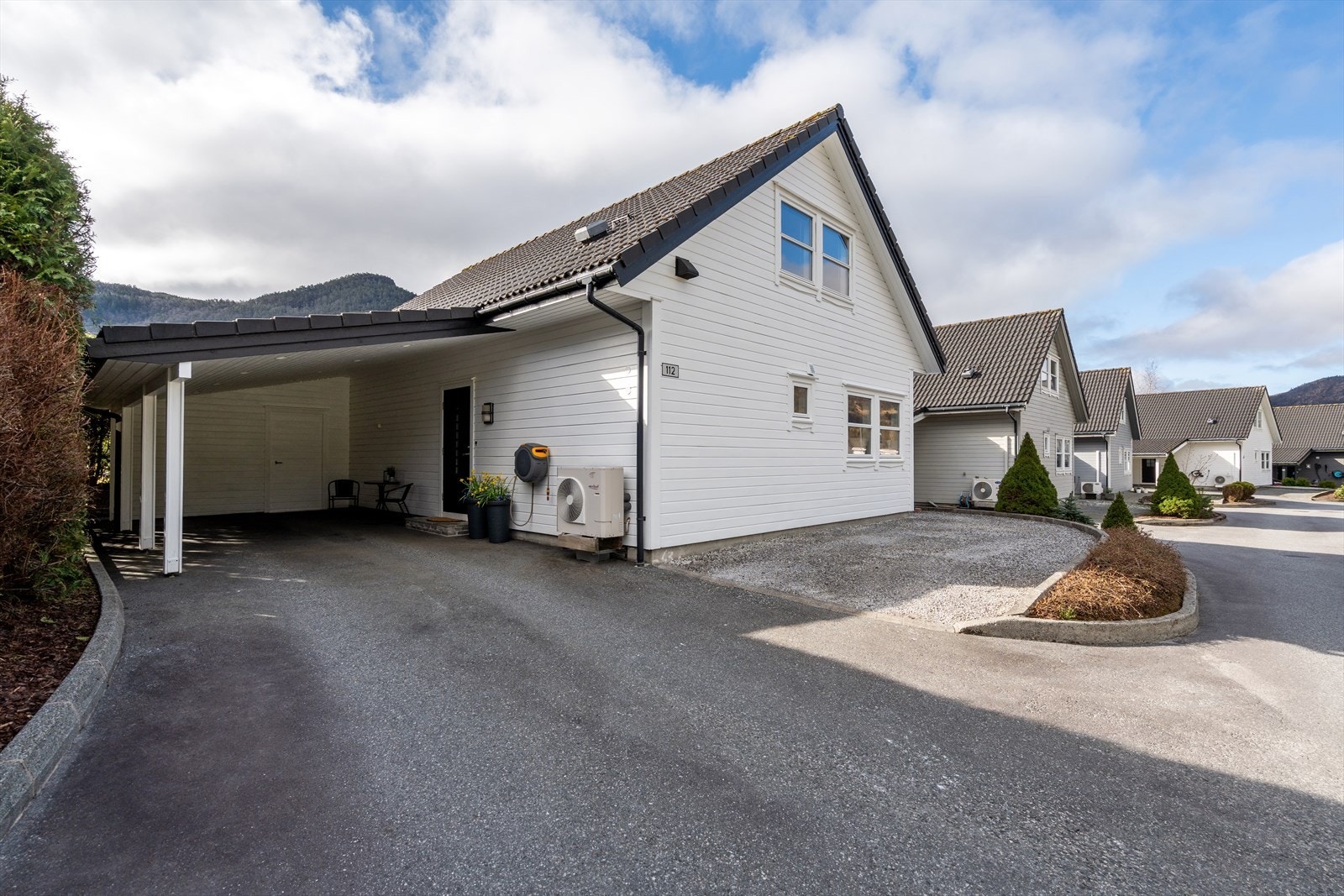 Asfaltert gårdsrom og parkering i carport. Galleribilde
