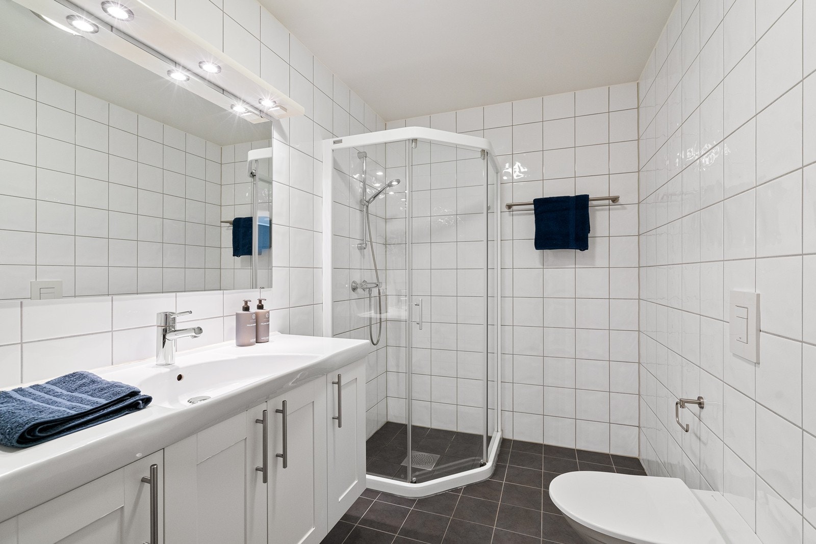 Badet i første etasje har nedfelt servant i skapseksjon, vegghengt toalett og dusjhjørne. Galleribilde