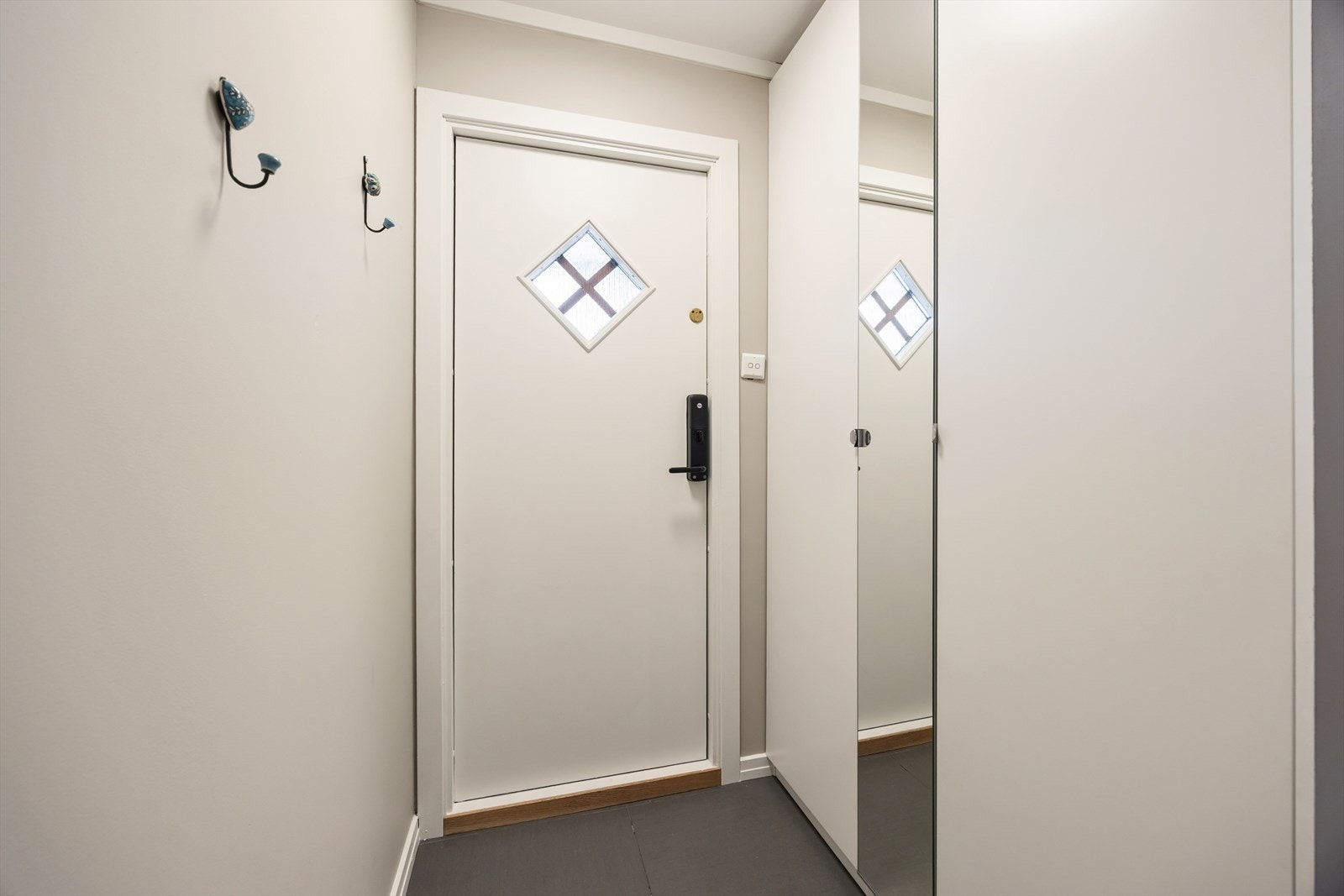 Lys og ryddig entré med fliser på gulv og plass til oppbevaring i garderobeskap. Galleribilde