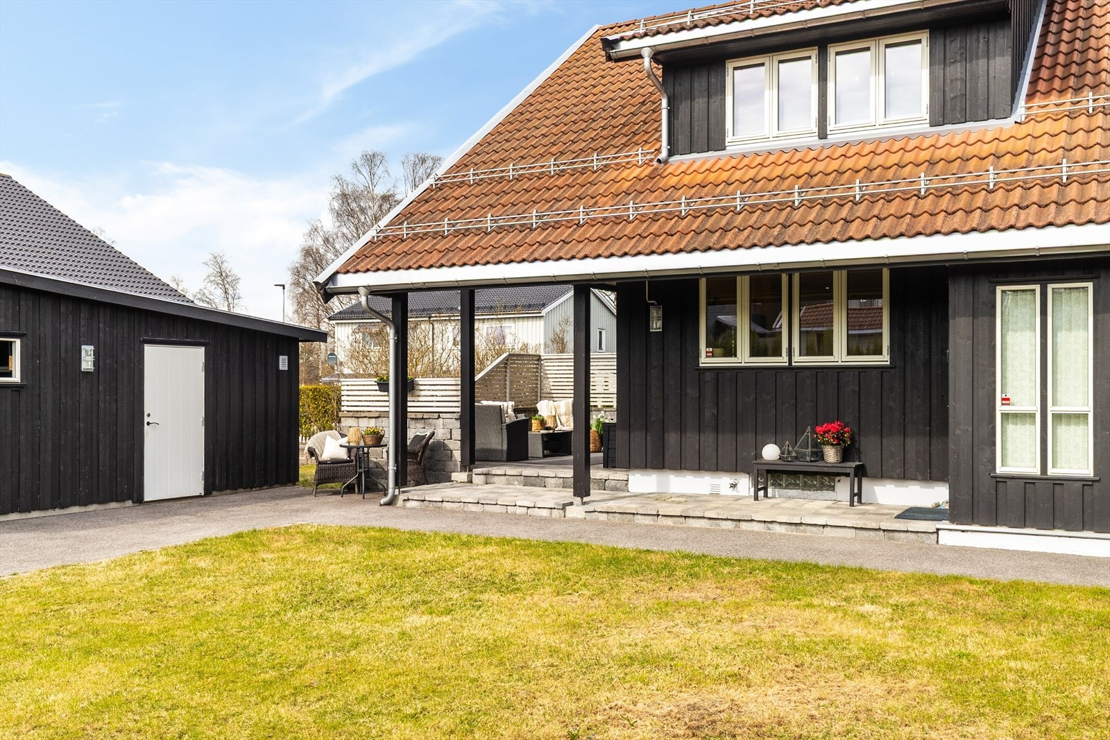 En overbygd uteplass i tilknytning til boligen og garasjen skaper en lun og skjermet sone. Galleribilde