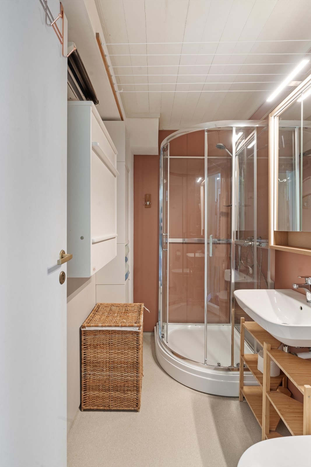Badet er innredet med dusjkabinett, vegghengt servant og gulvstående toalett. Galleribilde