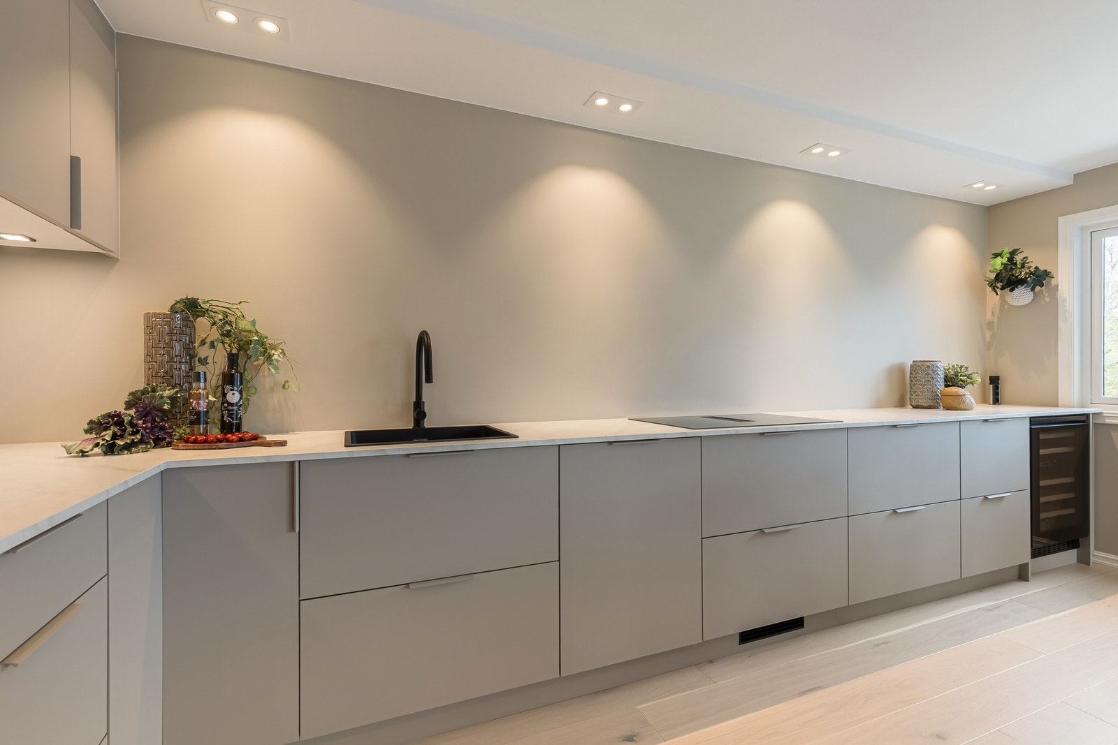 Moderne kjøkken med integrert ventilator i koketopp og stilrene spotlights i taket som gir et elegant uttrykk og optimal belysning. Galleribilde