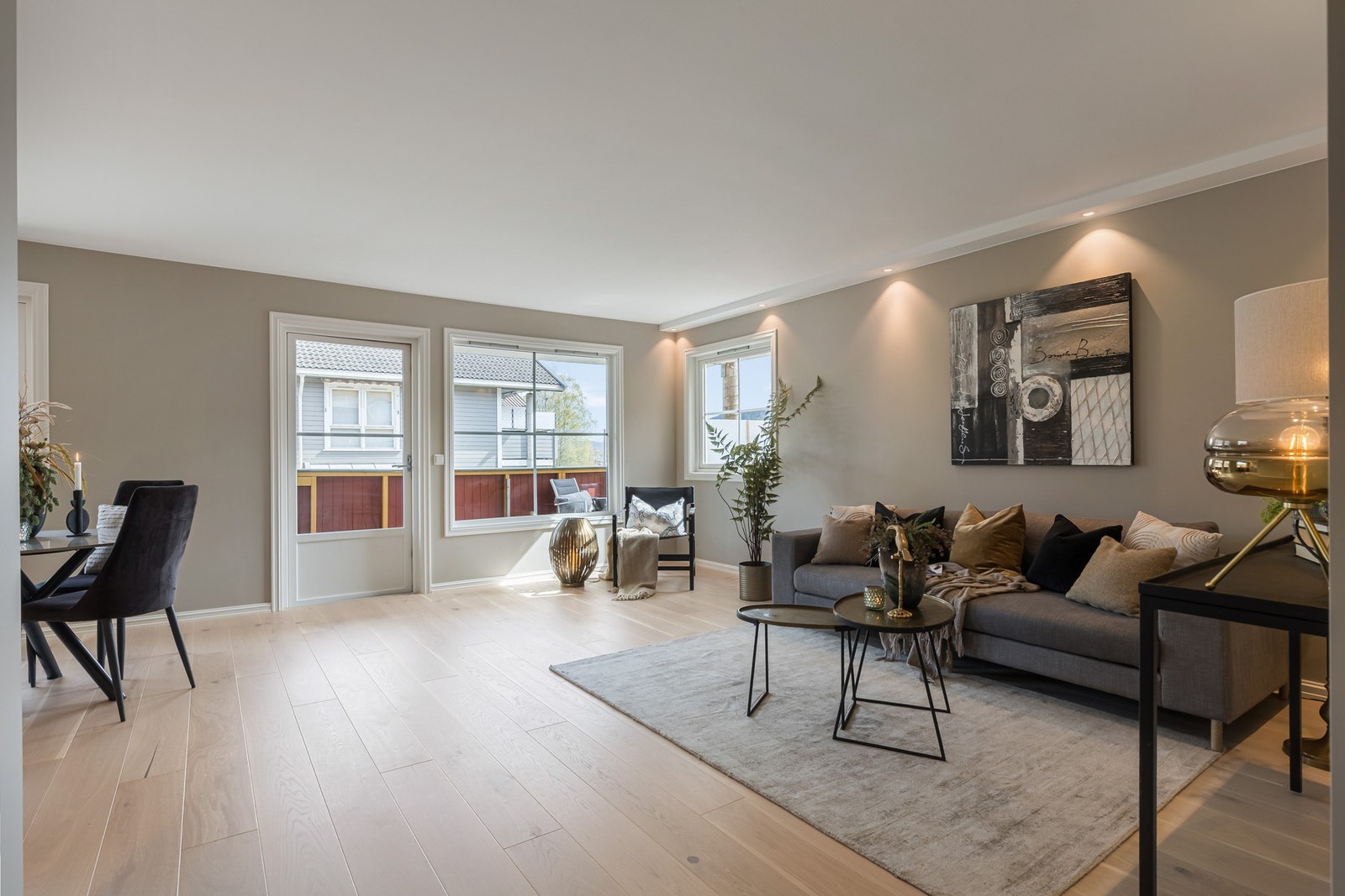 Lys og romslig stue med gjennomgående 1-stavs eikeparkett, slette vegger og stilrene spotlights som skaper en moderne og lun atmosfære. Galleribilde