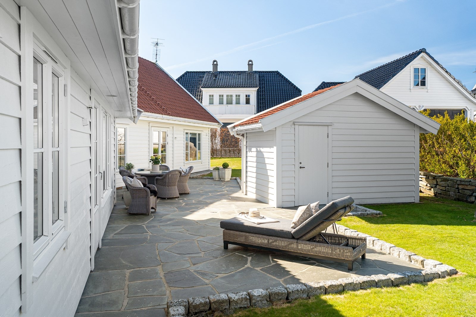 Uteområdet er nydelig opparbeidet med skiferplatting, steinmurer og gressplen Galleribilde