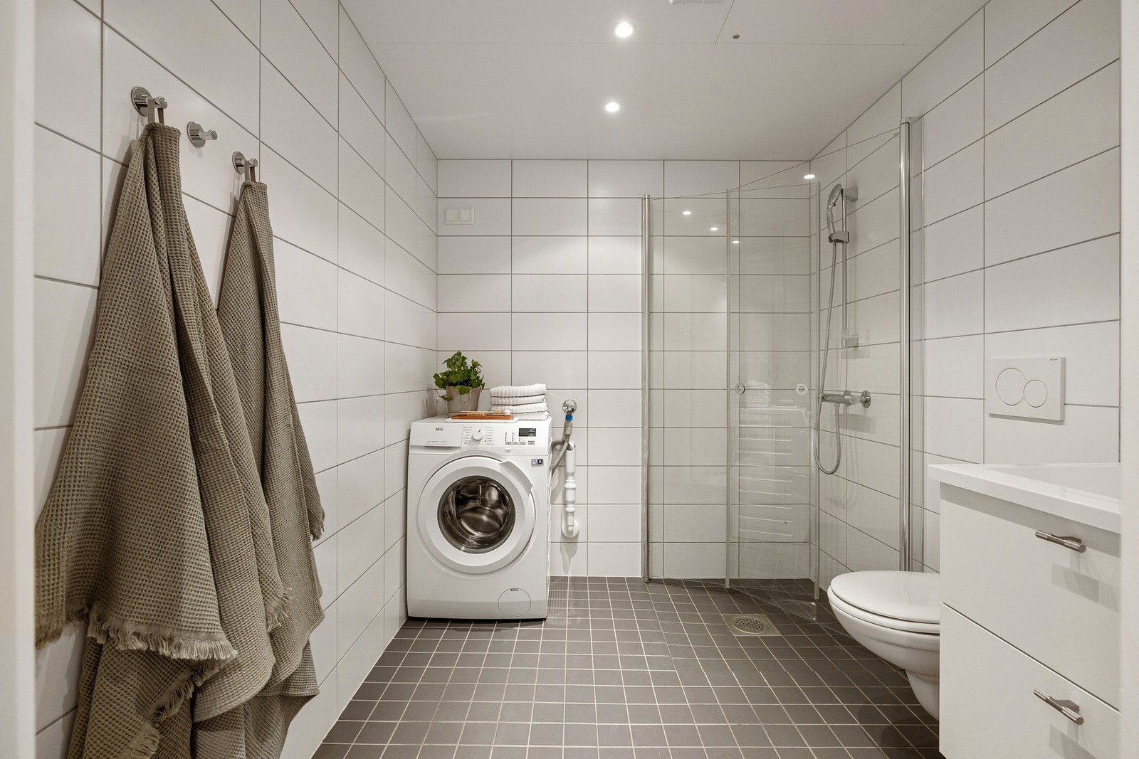 Leiligheten har et lyst og moderne baderom fra byggeåret 2015. I hjørnet er det plass og opplegg for vaskemaskin, samt tørketrommel over om ønskelig. Galleribilde