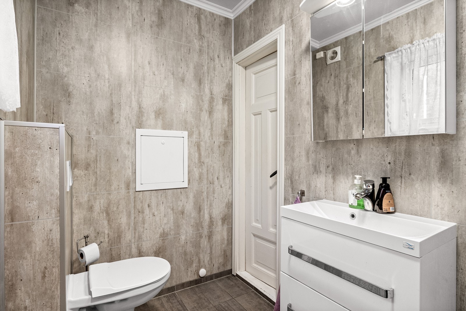 Badet er utstyrt med vegghengt toalett og servantinnredning med speilskap og belysning. Galleribilde