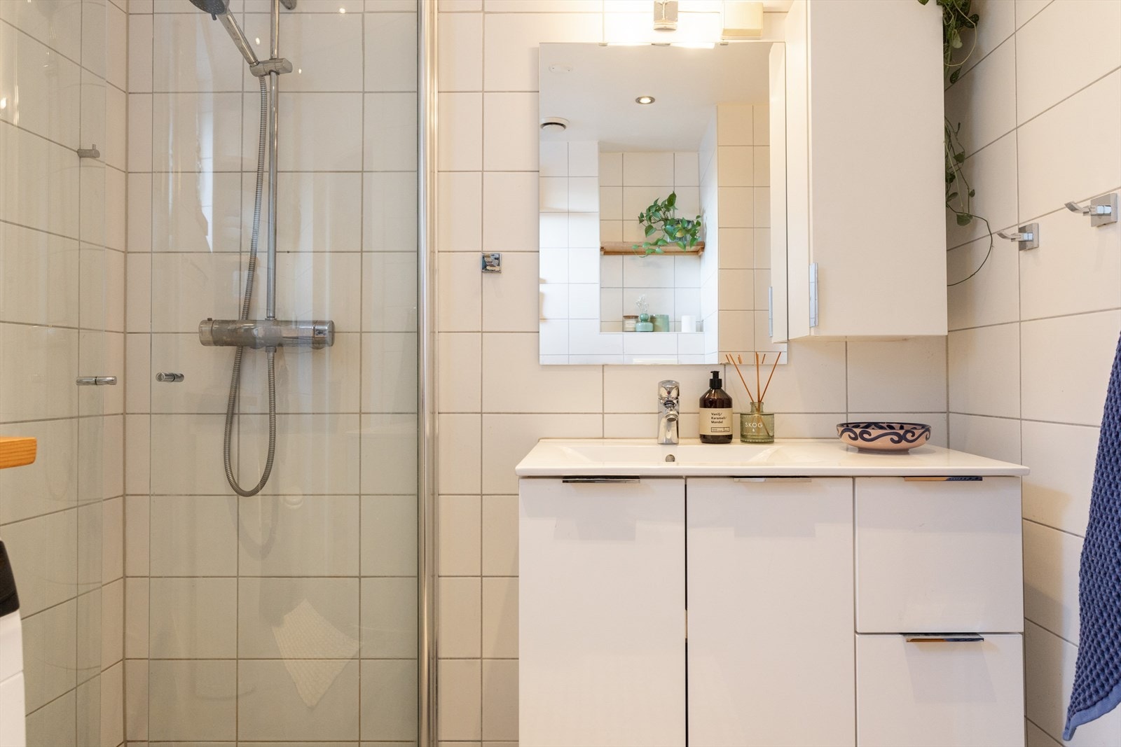 Badet er innredet med nedfelt servant og speil med overlys. I hjørnet finner du en dusjsone med håndholdt armatur og dusjvegger. Galleribilde