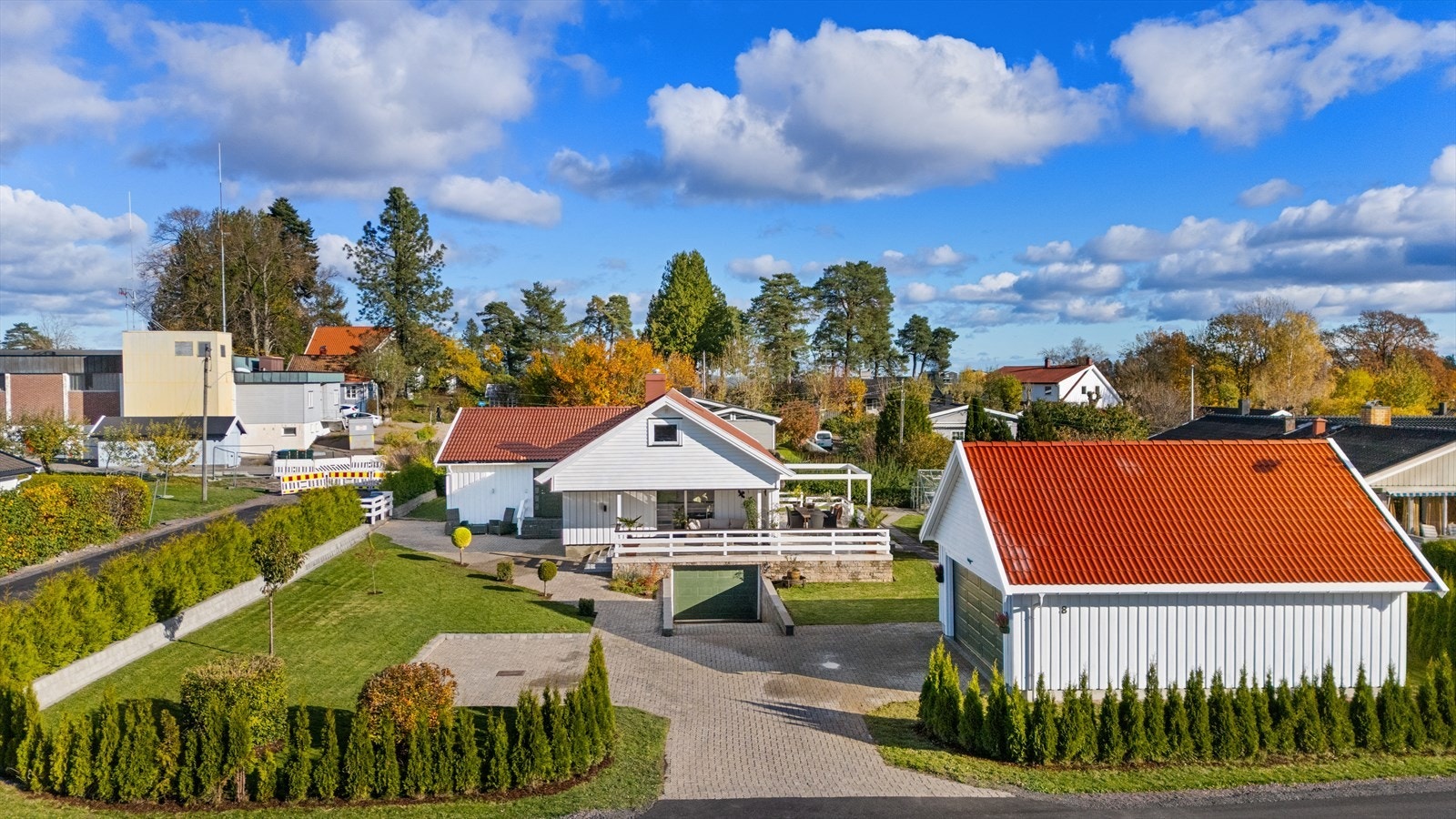 Pent opparbeidet uteområde med belegningsstein og hekk rundt tomten Galleribilde