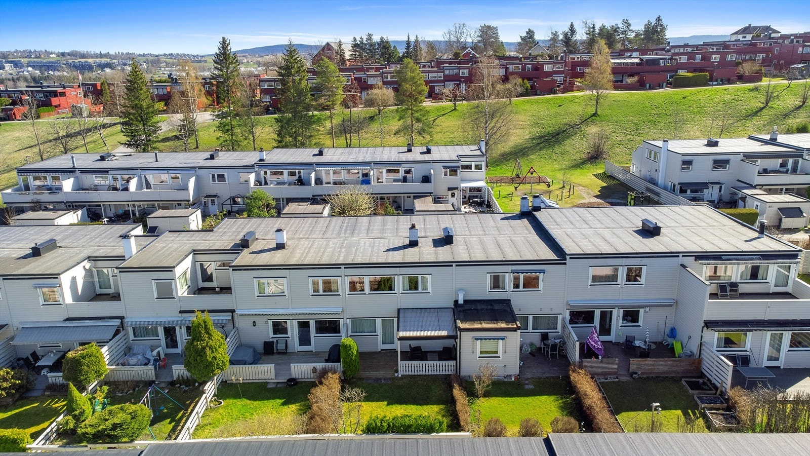 Fine fellesarealer med gressplener og lekeapparater mellom boligrekkene. Galleribilde