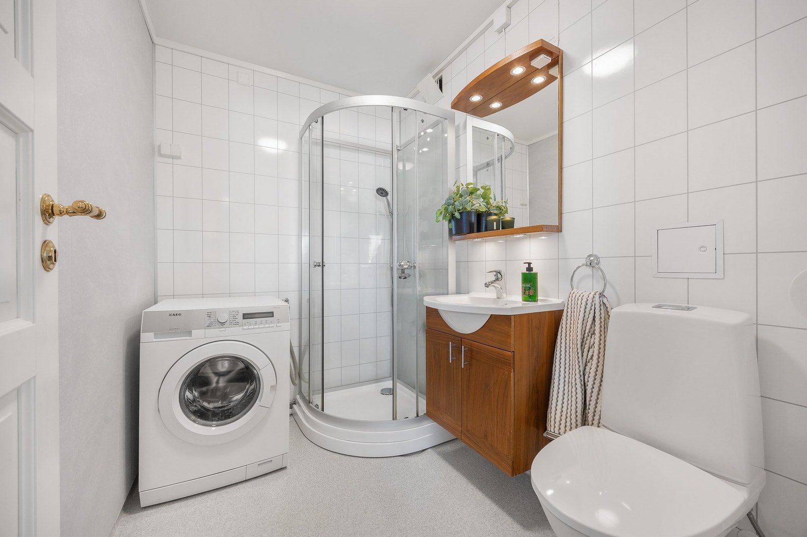Bad i første etasje med dusjkabinett, toalett og opplegg for vaskemaskin. Galleribilde