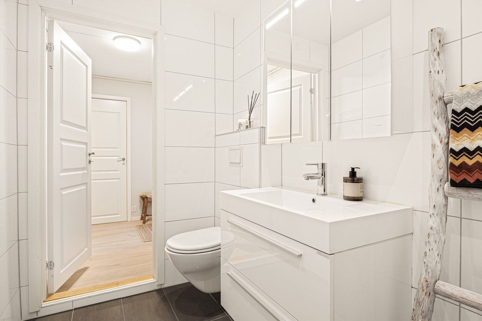 Badet er pent innredet med nedfelt servant, vegghengt toalett, opplegg til vaskemaskin og dusjhjørne/vegger. Galleribilde