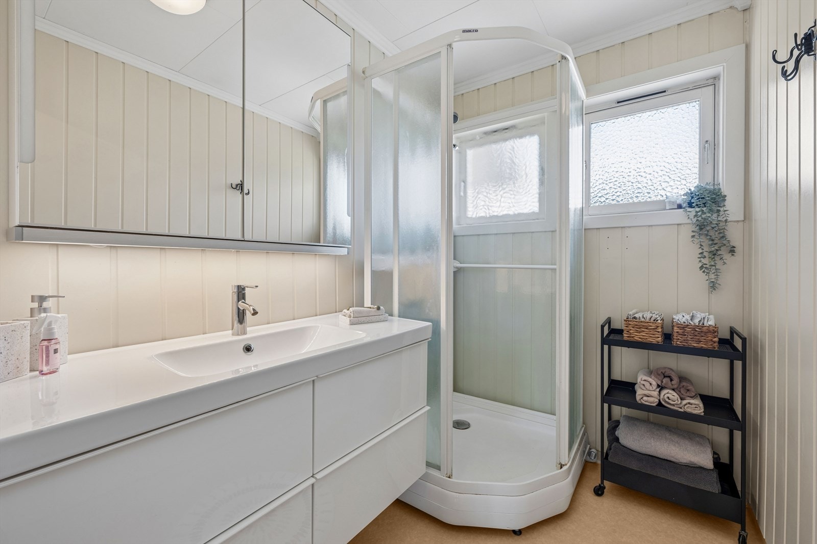Badet er utstyrt med baderomsinnredning med nedfelt servant og speilskap, samt et dusjkabinett. Galleribilde