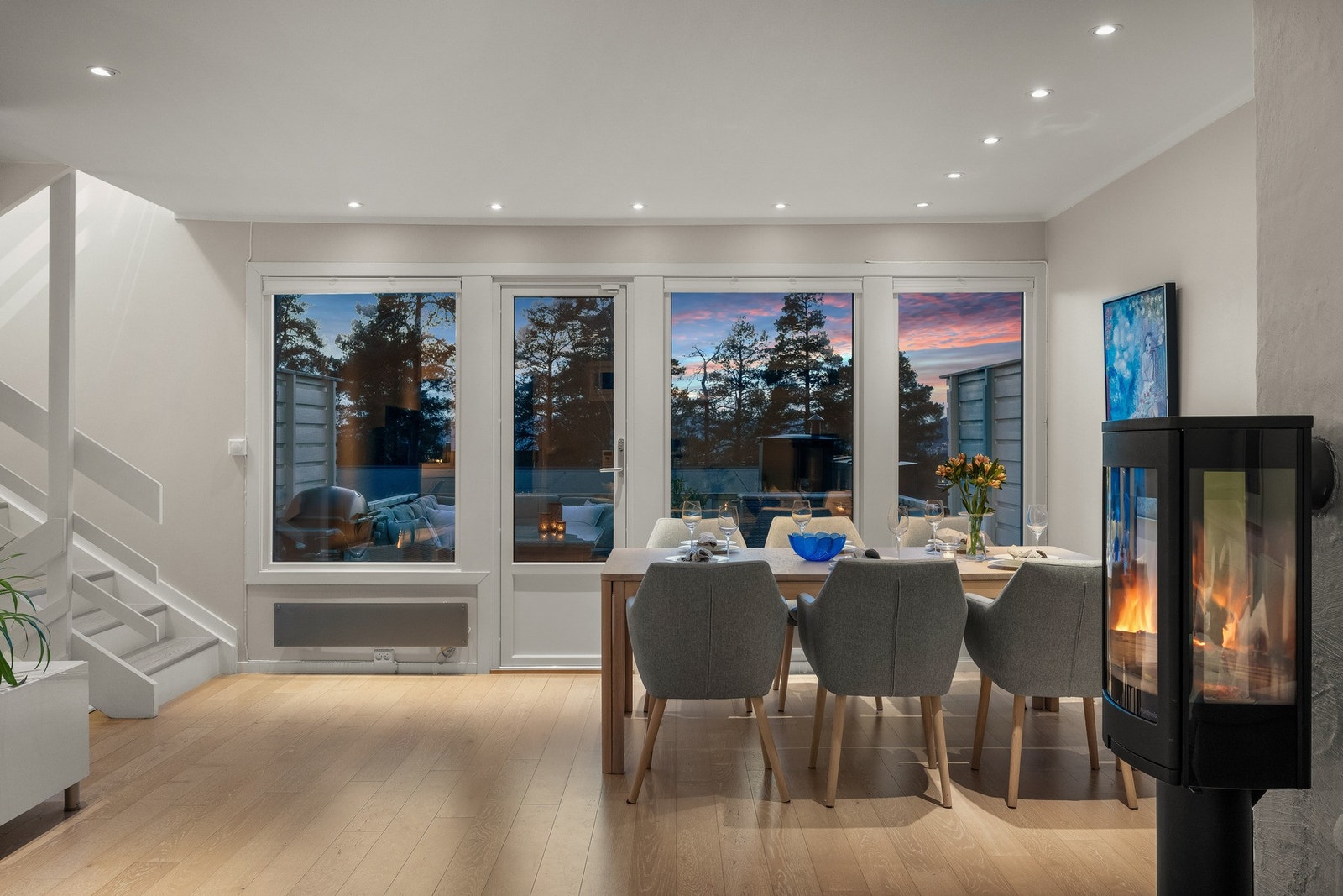 Spiseplassen rammes inn av store vindusflater med utsyn i kveldens lys. Galleribilde