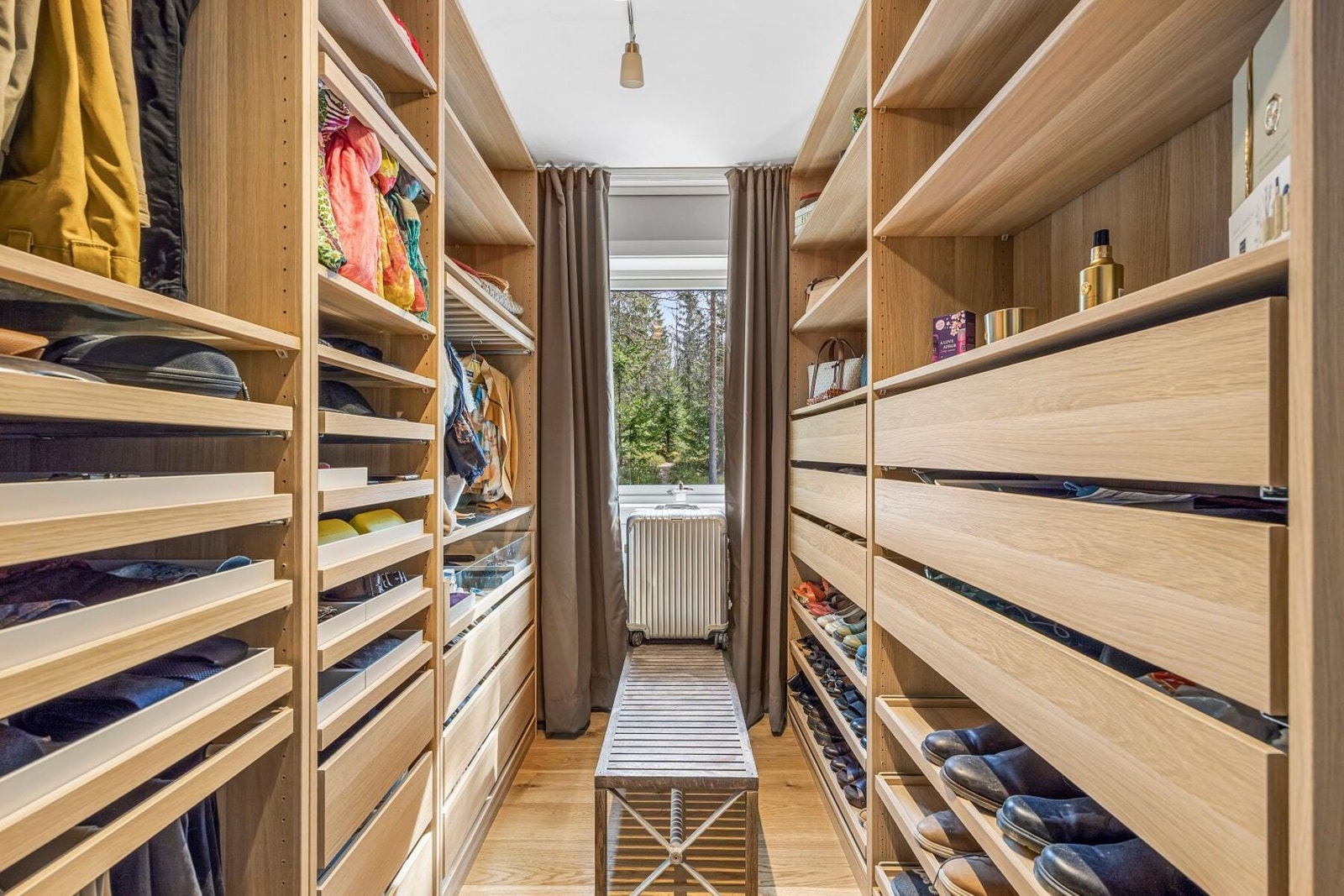 Funksjonell walk-in garderobe med gode oppbevaringsløsninger, innredet med både hyller og skuffer. Galleribilde