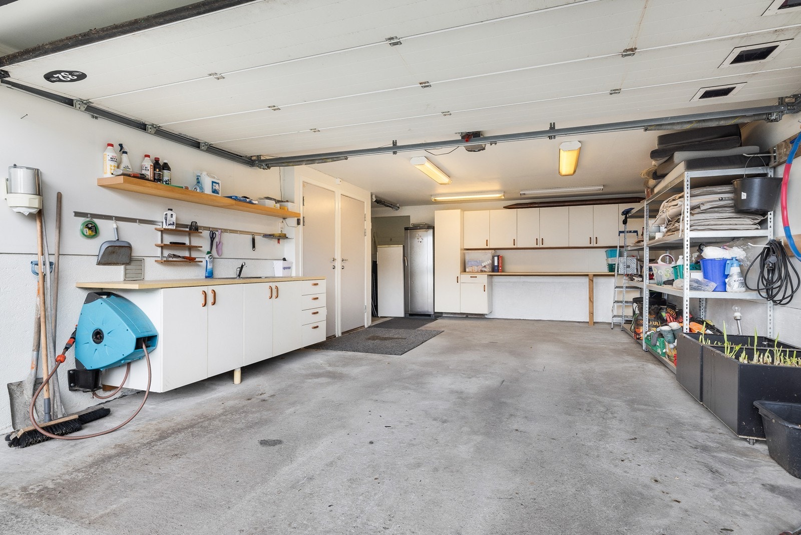 Stor garasje med gode oppbevaringsmuligheter og verkstedbenk med vask. Galleribilde