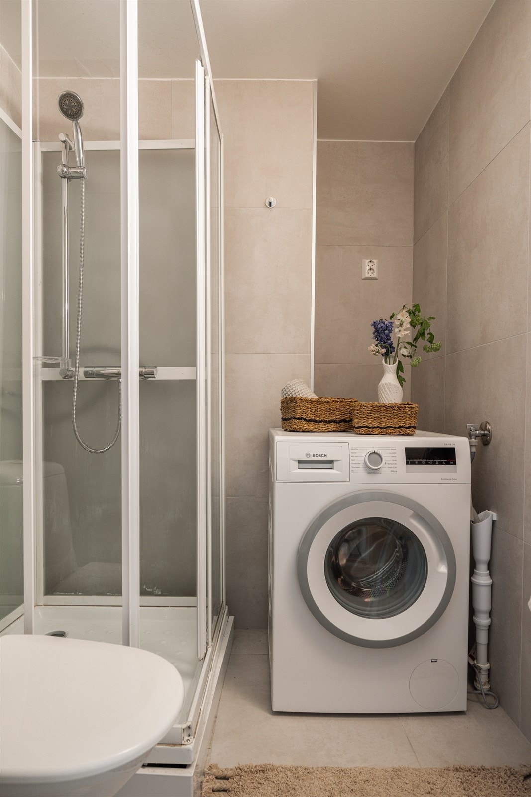 Det arealsmarte badet har tidløse lyse fliser på gulv og vegger. Galleribilde