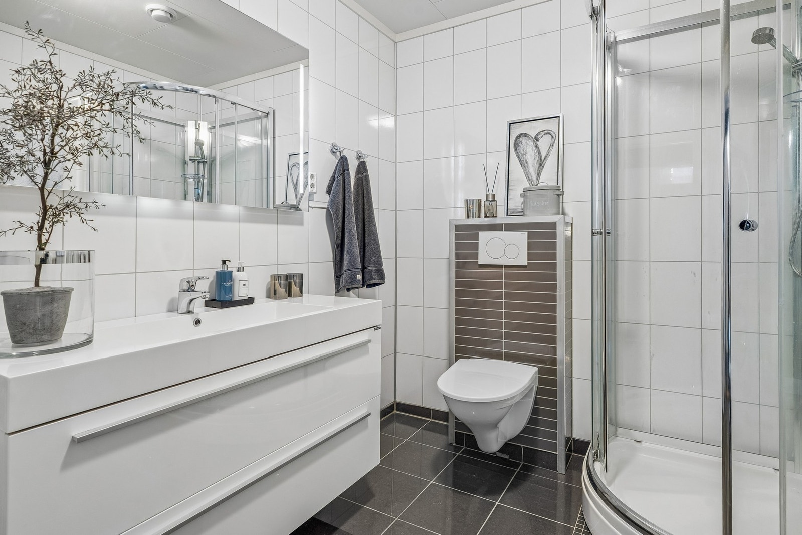 Her ligg alt til rette for orden og system på badet, med stilfull innreiing med store skuffer og praktisk veggskap Galleribilde