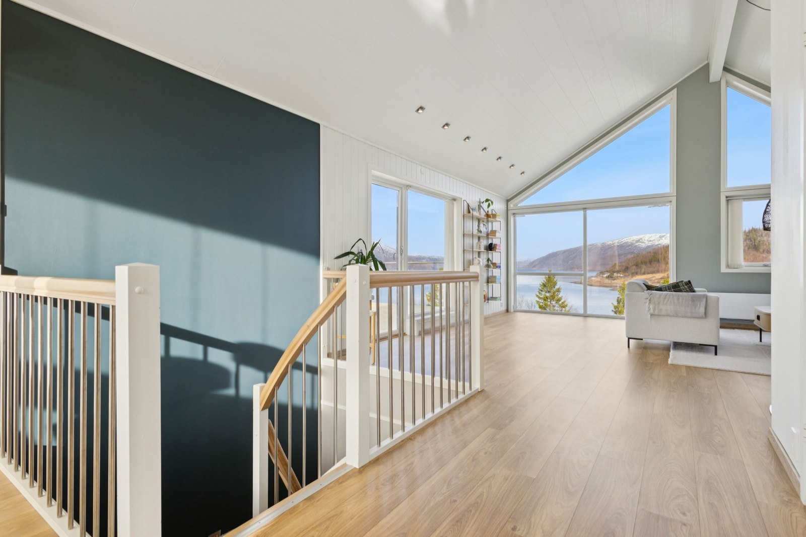 Vel oppe i andre etasje åpner rommet seg med en fantastisk takhøyde og panoramavinduer mot fjorden. Galleribilde