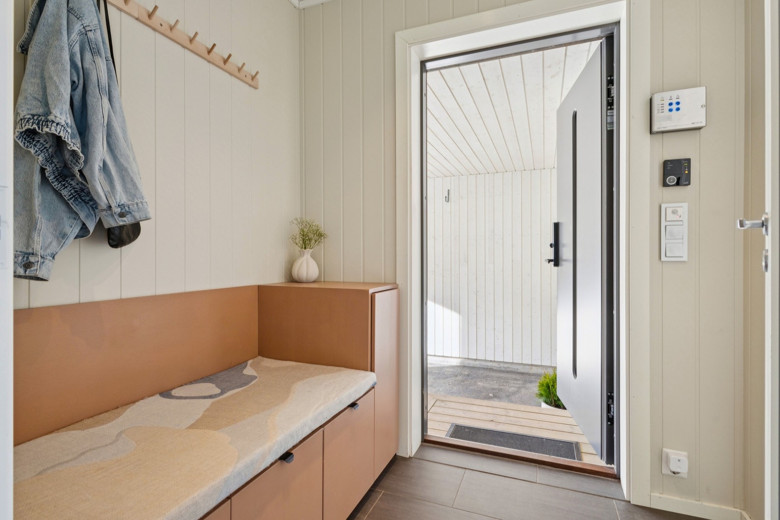 Entréen ønsker velkommen med en plassbygd sittebenk som gir praktisk oppbevaring for yttertøy og sko. Galleribilde