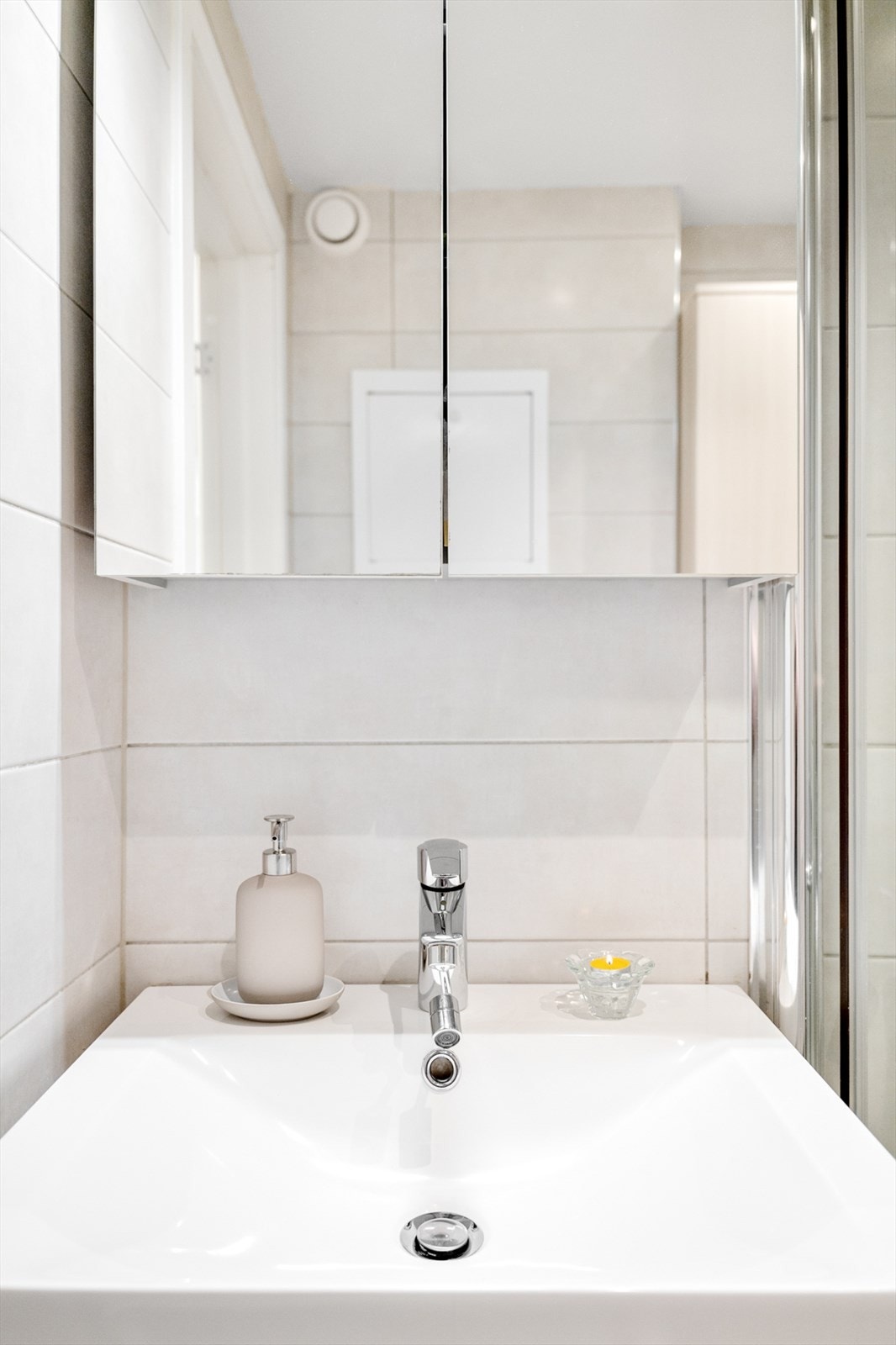 Videre er badet innredet med servantskap, speilskap med belysning, høyskap og veggmontert toalett, et pent og funksjonelt baderom. Galleribilde