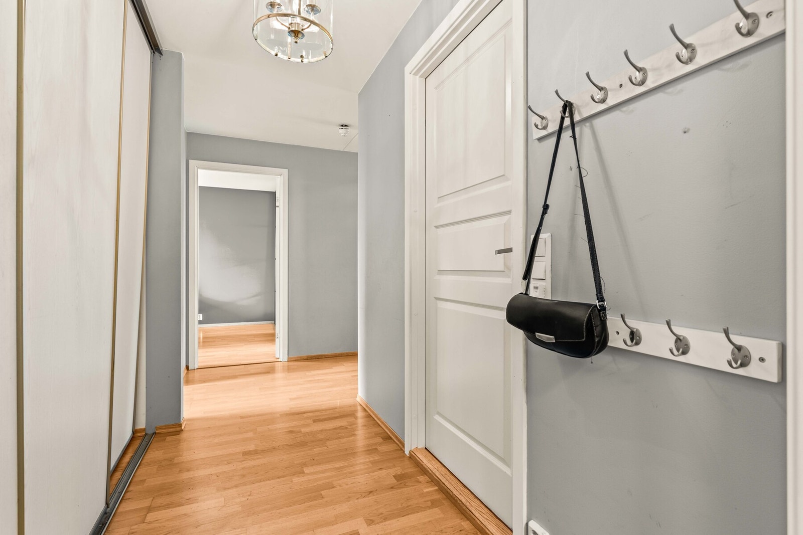 Praktisk entre med vegghengte knagger og plassbygd skyvedørsgarderobe. Galleribilde