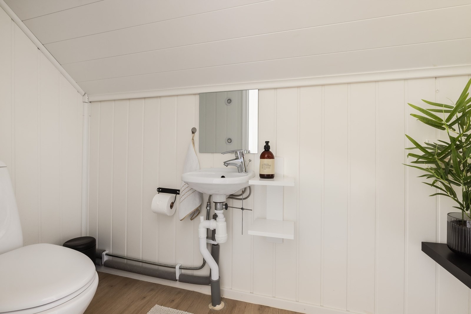 Separat toalettrom i 2. etasje med laminatgulv og panelvegger. Rommet har gulvmontert toalett og servant på vegg. Galleribilde