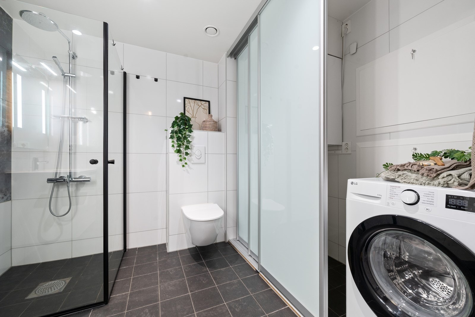 Badet er utstyrt med dusjhjørne, veggmontert toalett og opplegg for vaskemaskin. Galleribilde