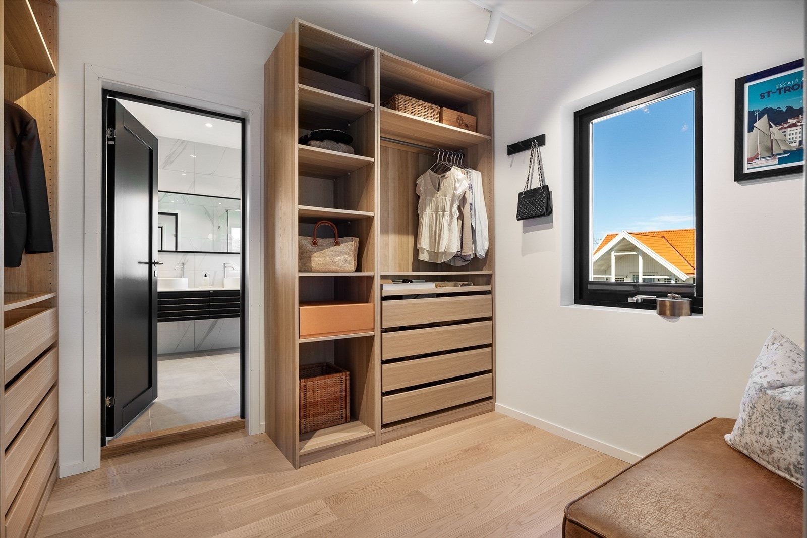 Romslig walk-in closet med fastmonterte garderobeløsninger, plassert mellom soverom og bad. Galleribilde