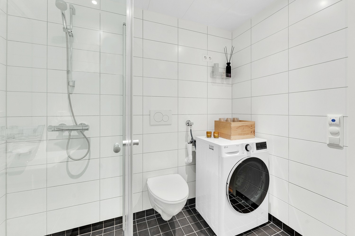 Innredet med heldekkende servant over innredning, speil med lys over, dusjhjørne - garnityr på vegg, vegghengt toalett og opplegg for vaskemaskin. Galleribilde