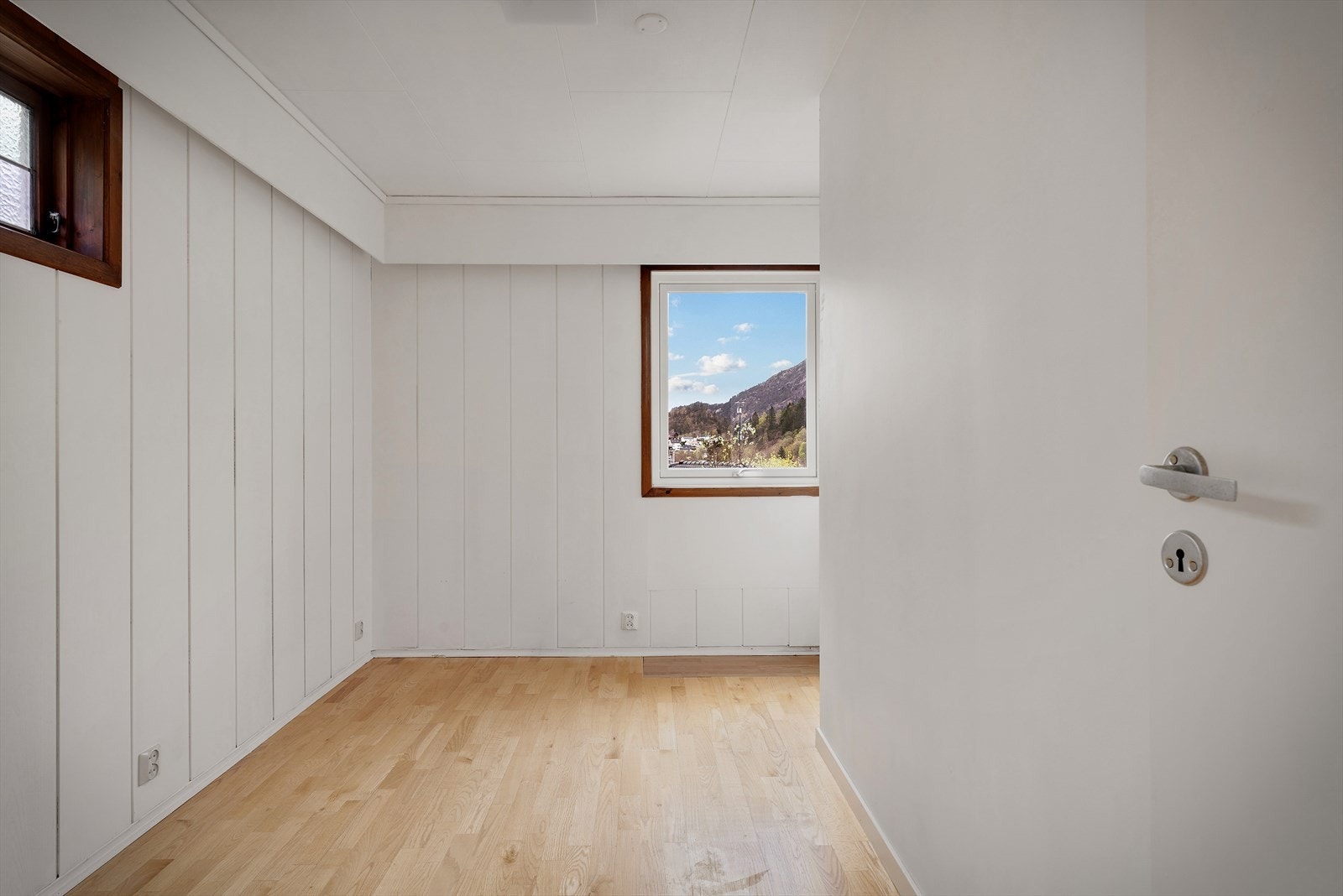 Et av soverommene i andre etasje, med parkett på gulv og malte panelvegger. Galleribilde
