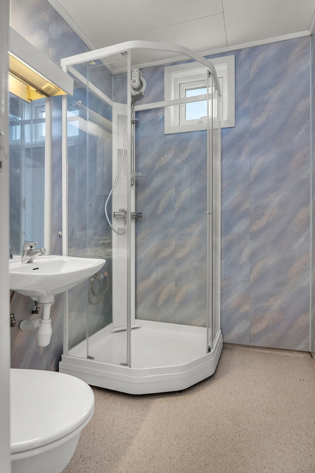 Badet er utstyrt med servant, toalett og dusjkabinett. Galleribilde