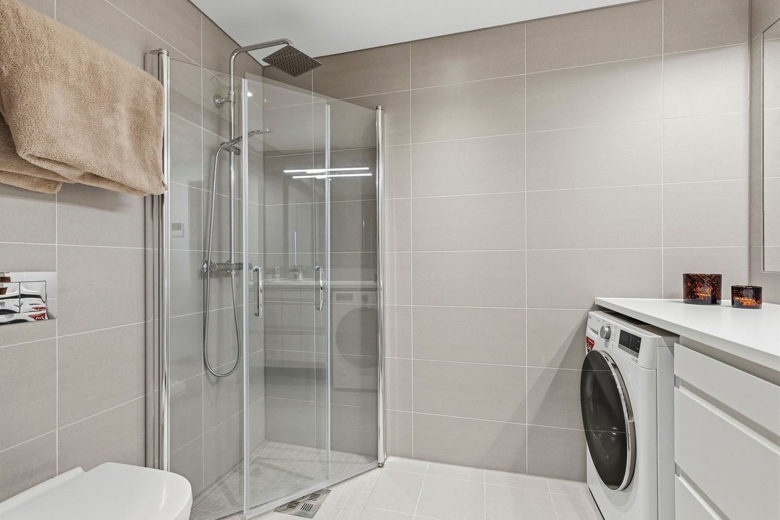 Badet har flislagte gulv og vegger, samt en slett himling som gir et rent uttrykk Galleribilde