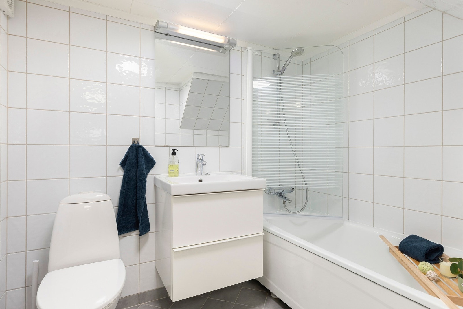 Helfliset baderom innredet med servant, toalett og badekar med dusj Galleribilde