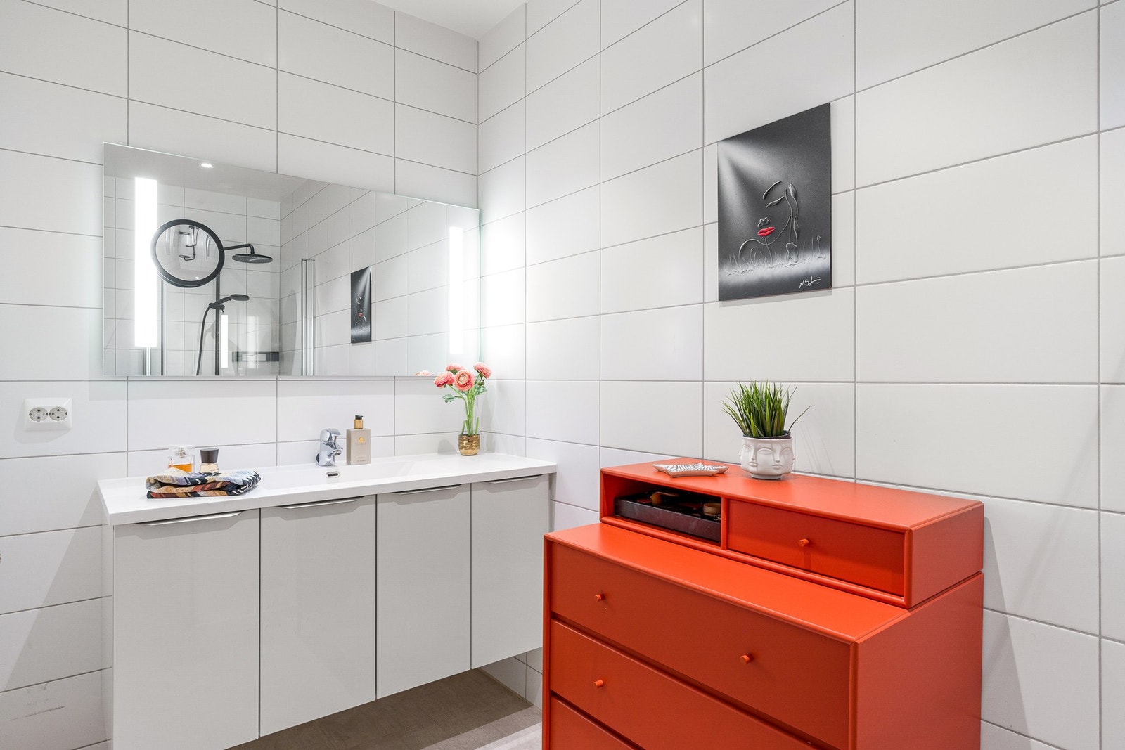 Badet er tidløst innredet, med gråbeige fliser på gulv, hvite veggfliser og varmekabler. Galleribilde
