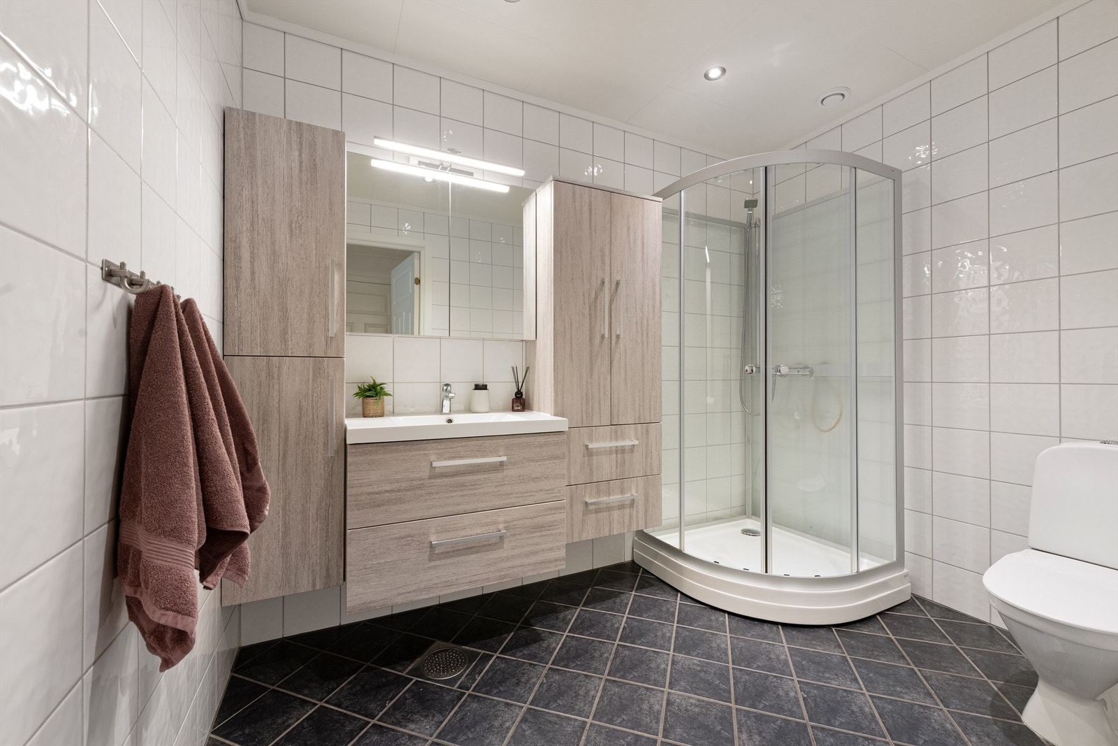 Badet i første etasje har flislagt gulv med gulvvarme, dusjkabinett og baderomsinnredning fra Lind, montert i 2017. Galleribilde
