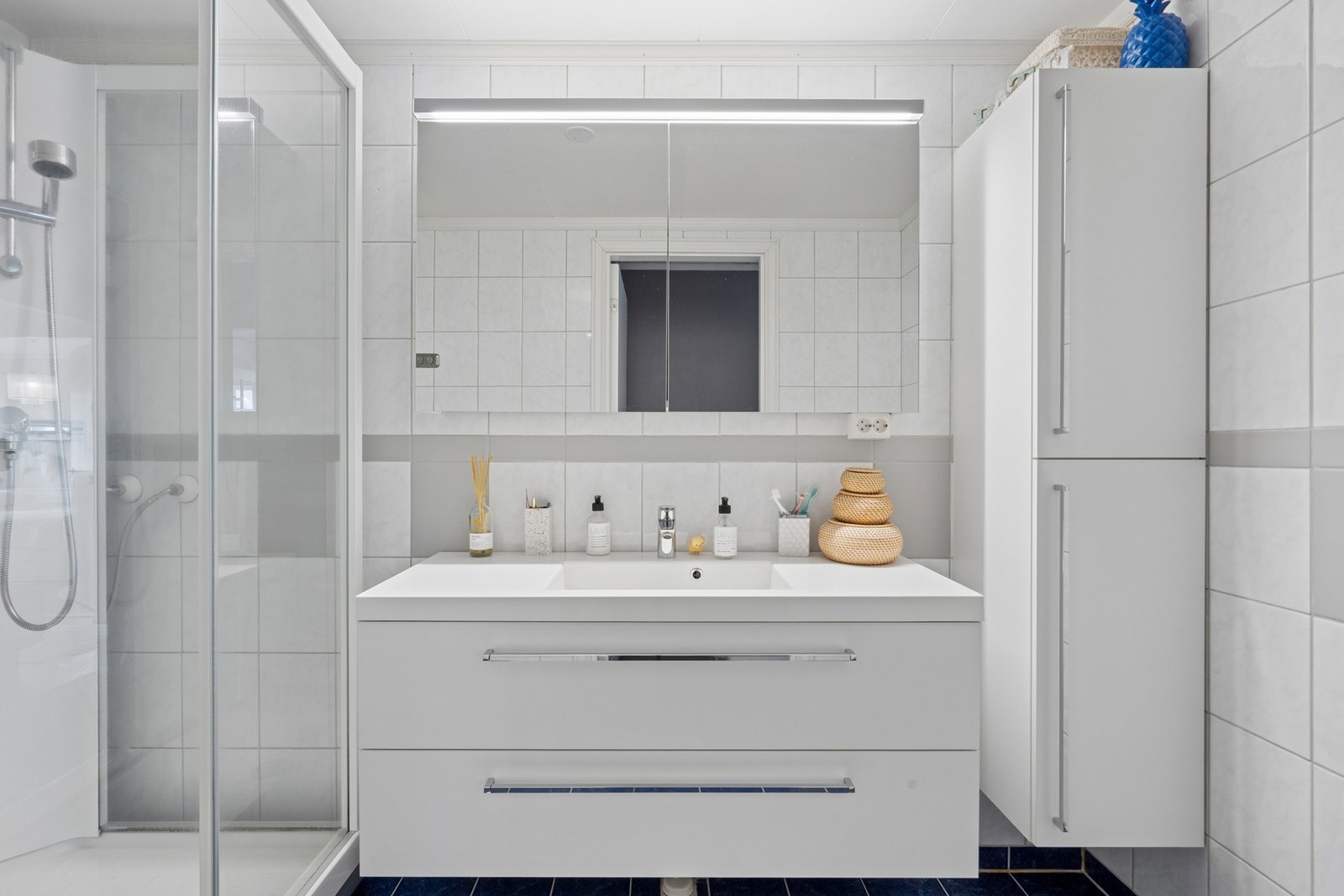 Badet har fliser på gulv og vegger. Innredningen med servant og dusjkabinettet er fra 2018. Galleribilde