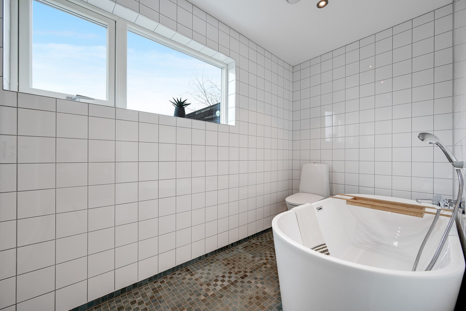 Badet i denne etasjen er helfliset, har gulvvarme og et frittstående badekar. Galleribilde