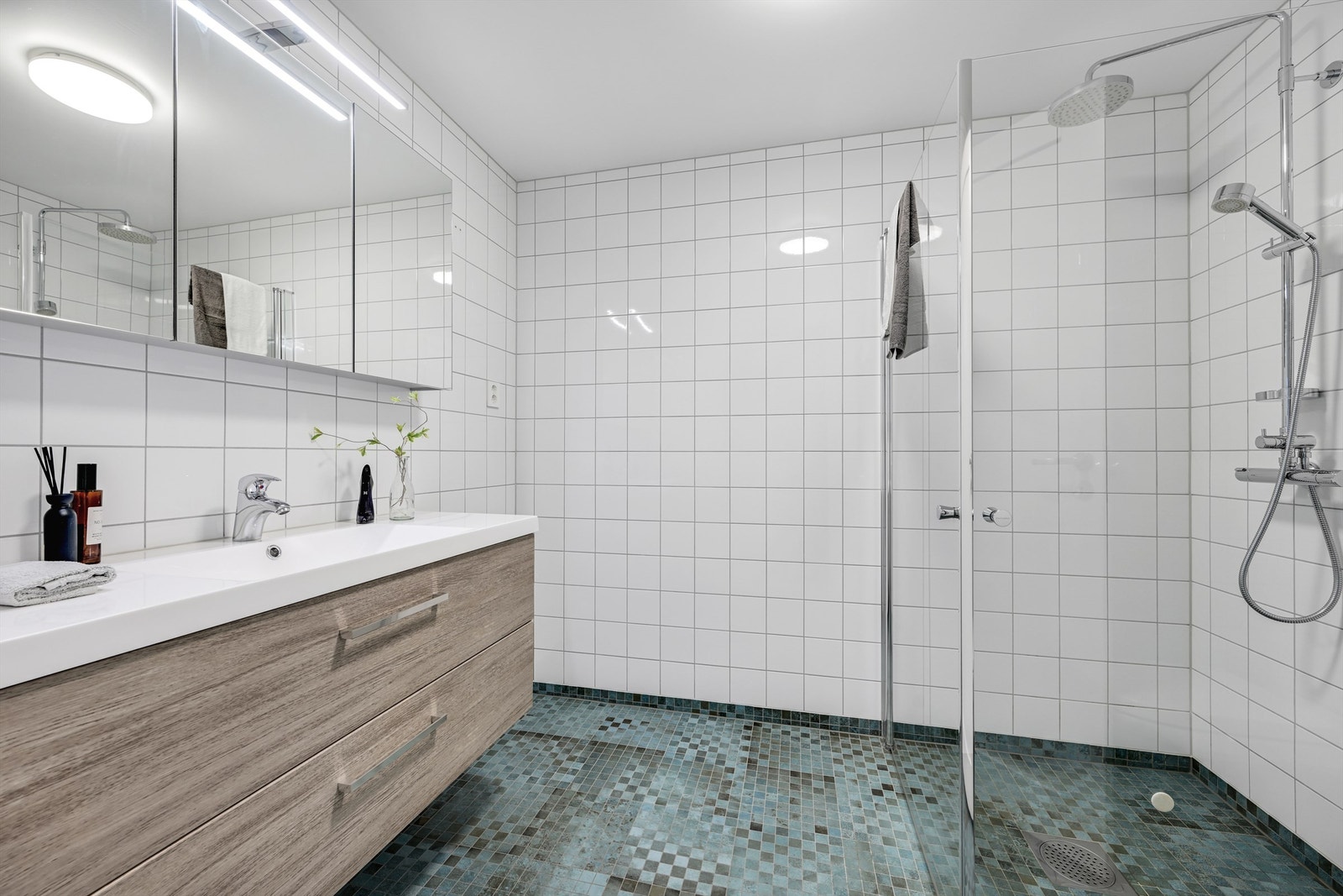 Badet i første etasje har fliser på gulv og vegger, gulvvarme og dusjhjørne med glassvegger. Galleribilde