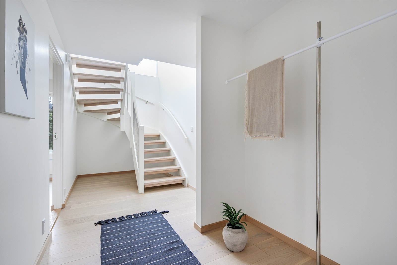 Hallen ønsker velkommen med parkett på gulvet og en malt tretrapp med eiketrinn som binder etasjene sammen. Galleribilde