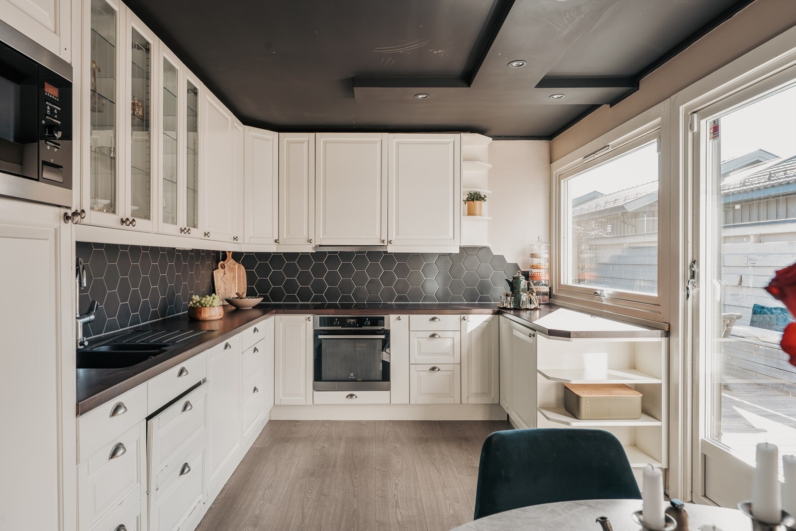 Innredningen har profilerte, fabrikklakkerte fronter og laminat benkeplate med planlimt kum i kompositt. Det er "Hexagon" fliser på vegg over benkeplate. Belysning via downlights under overskap. Galleribilde