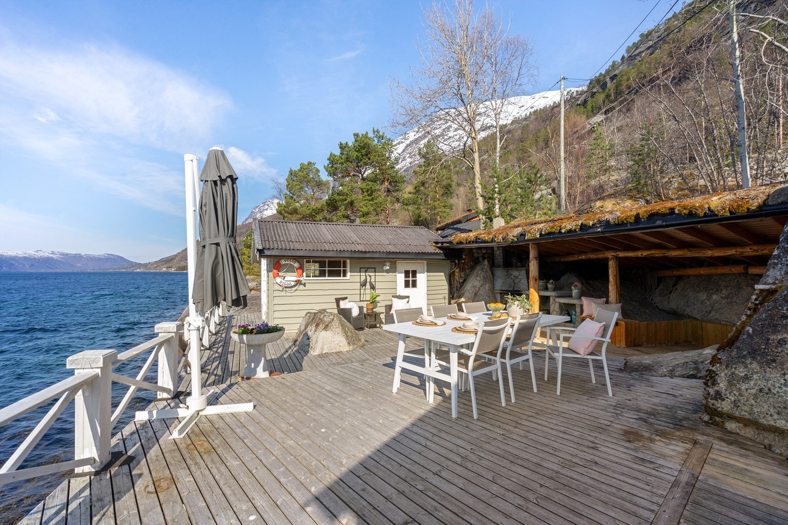 Området rundt hytten er opparbeidet med terrasse, peis, gangarealer og rekkverk langs sjøkanten. Galleribilde