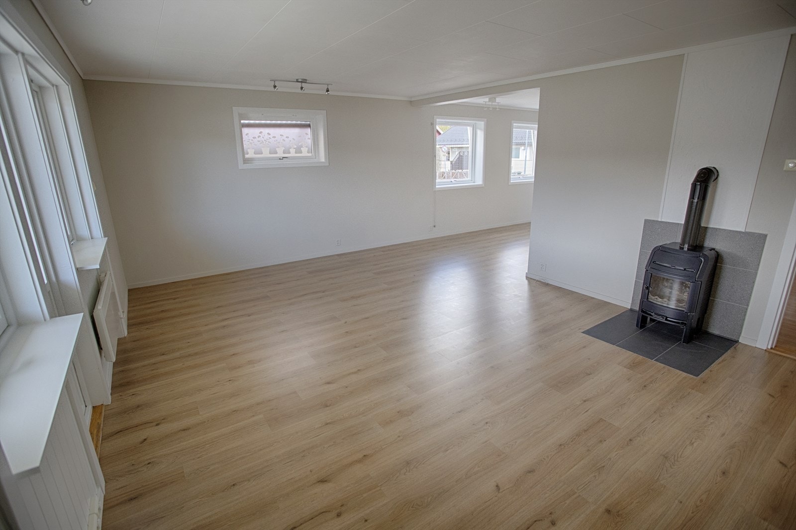 Romslig stue med laminatgulv og malte flater, som gir rikelig med plass for både sofagruppe og spisebord. Galleribilde