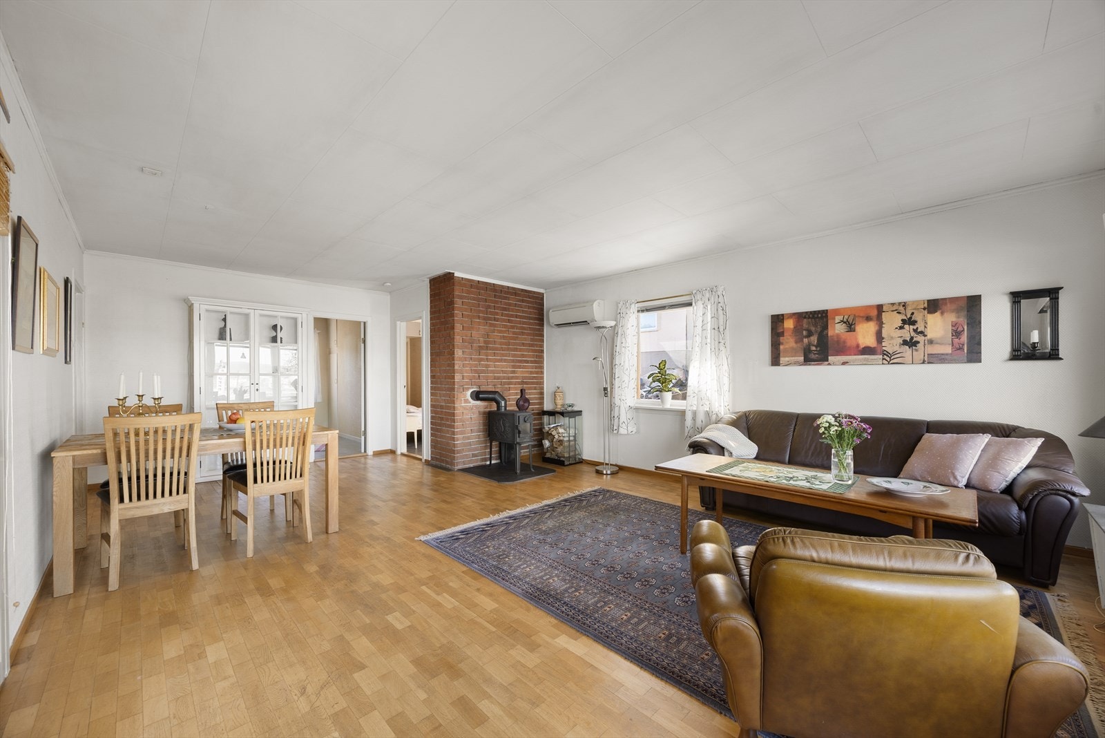 En sentralt plassert mursteinspipe med vedovn gir både varme og karakter til rommet. Galleribilde