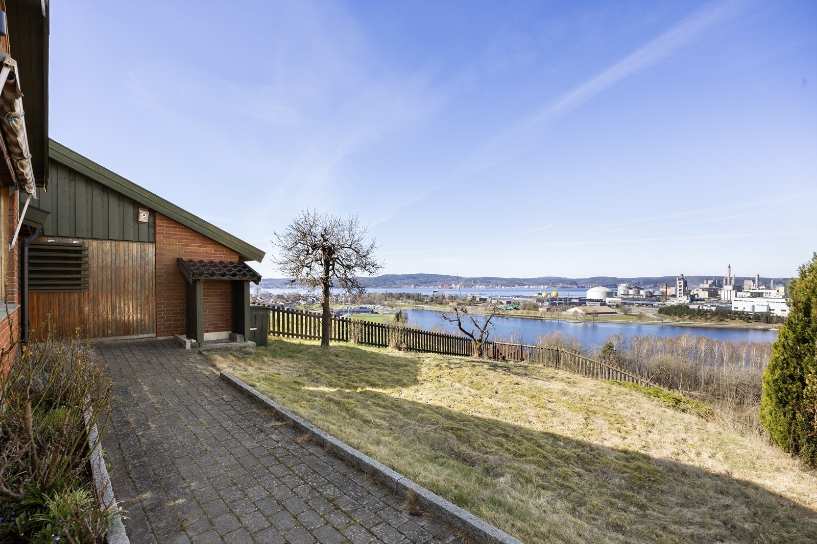 Eiendommen ligger på en skrånet tomt med belegningsstein i innkjørsel og gangarealer. Galleribilde