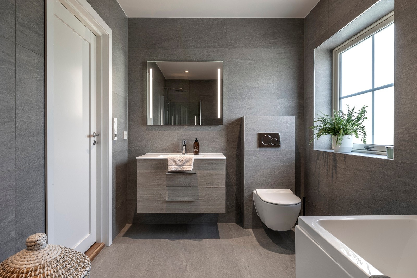 Badet har et moderne og tidløst design med vegg- og gulvfliser i grå toner. Galleribilde