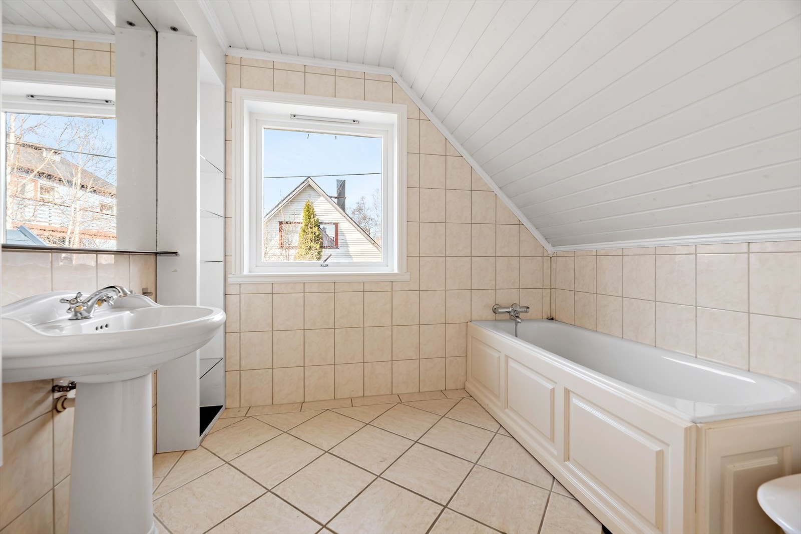 Badet er utstyrt med flislagte vegger og gulv, samt et badekar og servant. Galleribilde