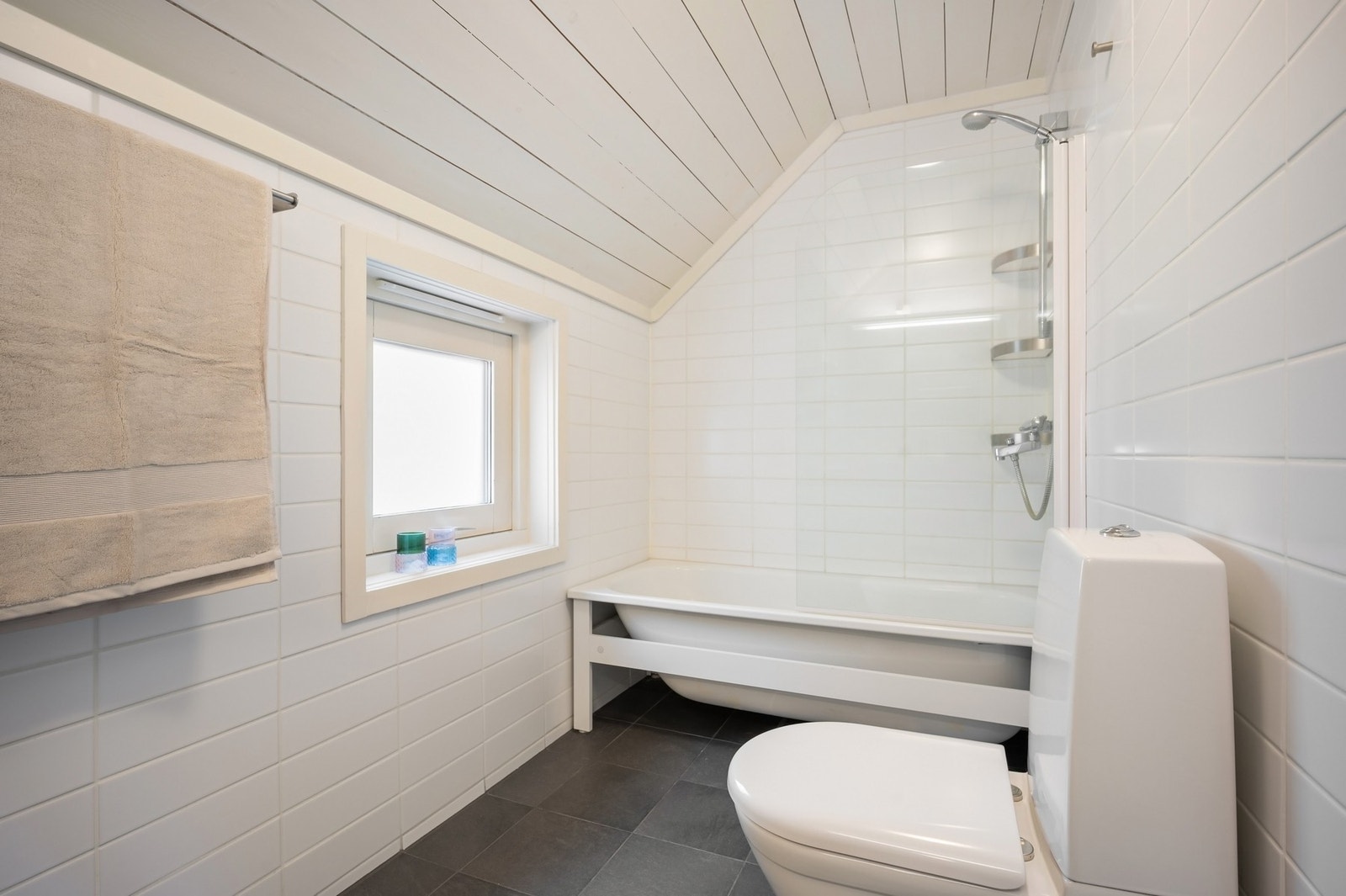 På badet er det toalett, varmekabler og badekar med dusjvegg av herdet glass. Galleribilde